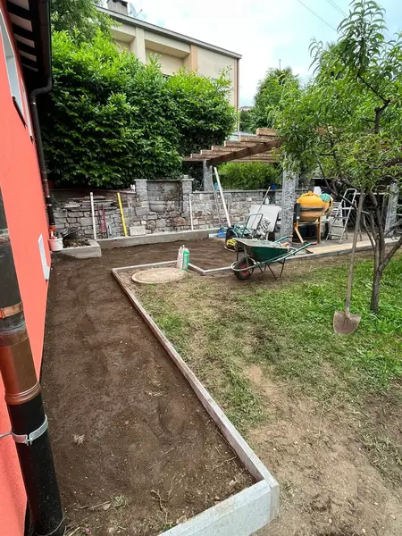 Cantiere di pavimentazione esterna con cordoli in cemento e aiuole in preparazione