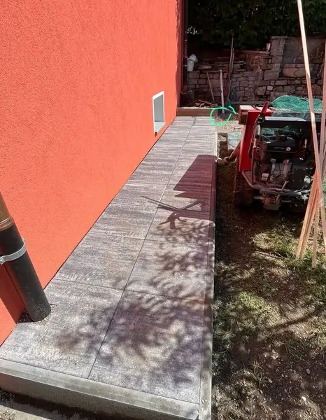 Vialetto pavimentato con grandi lastre grigie lungo la facciata di casa